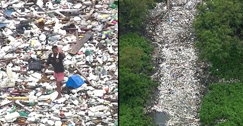 Homem anda em cima de um rio devido à quantidade de lixo acumulado